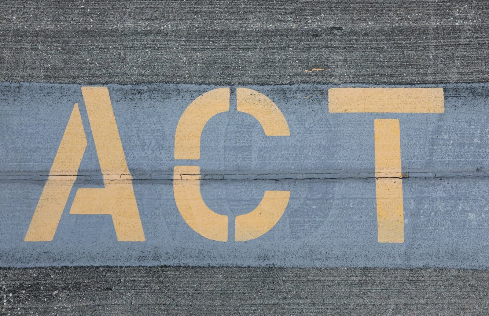 המילה ACT מצוירת באותיות צהובות גדולות על רצועה כחולה באספלט אפור
